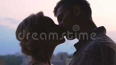 年轻夫妇在天空城市风景背景下接吻，青春的爱情，相聚